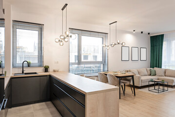 Modern interior of kitchen with living room. Wooden furniture of kitchen with counter and wooden floor in room with sofa. empty frame on the wall. Real estate.