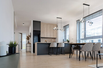 Modern dining room with kitchen. Design interior with wooden floor, furniture and table with chairs. Minimalist and contemporary decor. in new apartment. Real estate.	