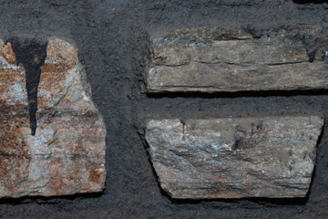 Detailed view of a rustic stone wall featuring varying stone sizes and colors, set against a backdrop of dark, coarse mortar
