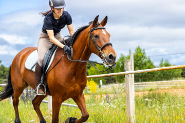 Woman riding a brown horse with focus in an outdoor arena