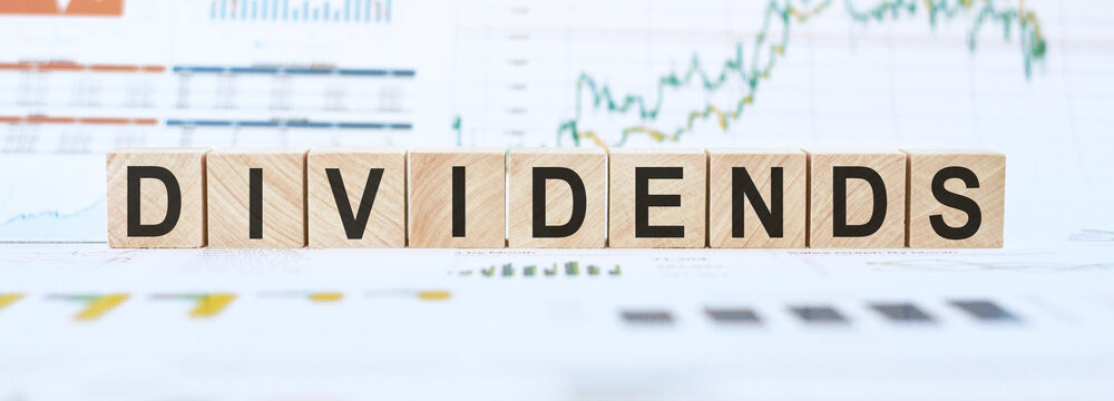 Wooden Blocks Spelling Dividends on a Financial Graph Background