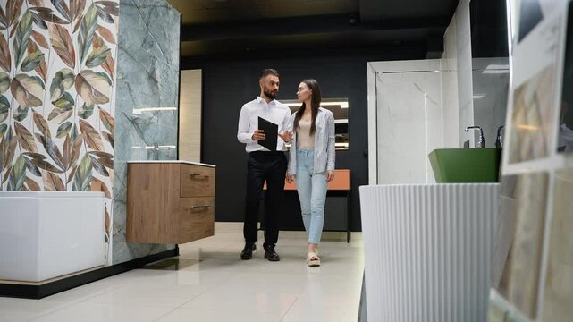 A sales consultant guides a customer through bathroom decor options in a tile showroom
