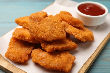 Delicious chicken nuggets with ketchup on blue wooden table, closeup