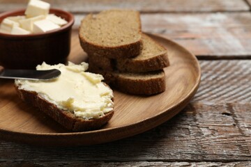 Fresh bread with butter and knife on wooden table, closeup