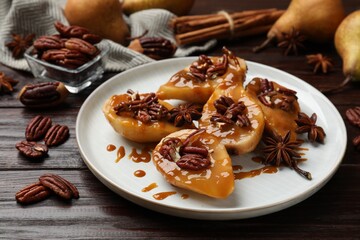 Delicious pears with caramel sauce, pecan nuts and anise stars on wooden table, closeup