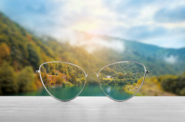 Glasses against beautiful landscape. View through lenses more clear. Vision correction