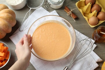 Woman making pumpkin pancakes at wooden table, top view