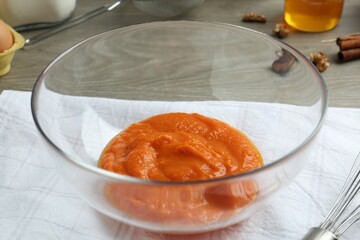 Bowl with pumpkin puree on wooden table, closeup