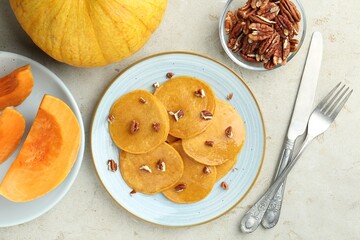Tasty pumpkin pancakes with nuts served on light grey table, flat lay
