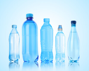Different plastic bottles with water on light blue background