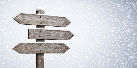 Blank wooden road sign against the backdrop of a snowy winter and falling snow, copy space