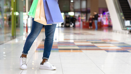 Black guy with shopping bags using cellphone in mall, messaging with friends, cropped image with free space