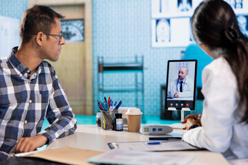 Indian physician entering a video call with expert to discuss diagnostic report, asking the specialist for a second opinion on remote videoconference. Doctors meeting online for telehealth.