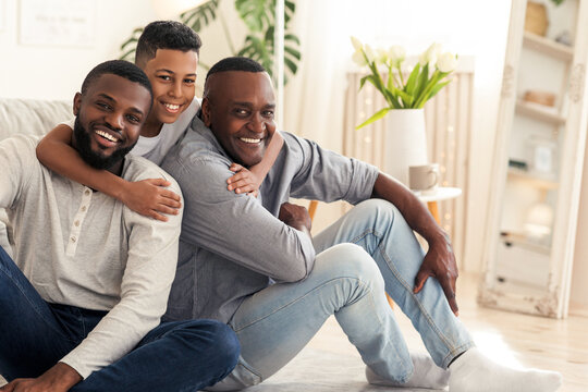 Generations. Preteen african american boy hugging dad and grandfather while posing together at home