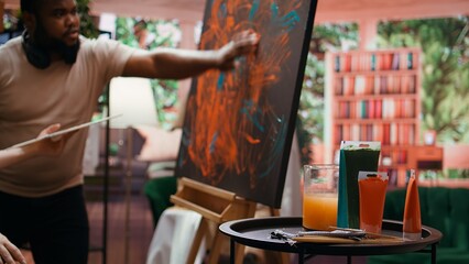 Team of artists in a gallery atelier working on a new art piece, using finger painting technique...