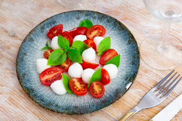Delicious fresh vegetable caprese salad with tomato and mozzarella served on plate