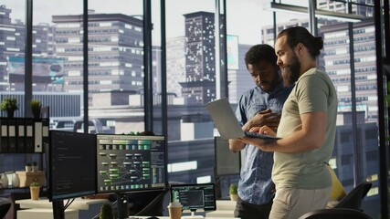 IT employees in office working together using laptop, testing and deploying programs and systems....