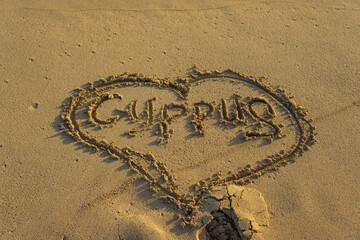 Heartfelt inscription in the sand expressing love for Cyprus on a tranquil beach at sunset....