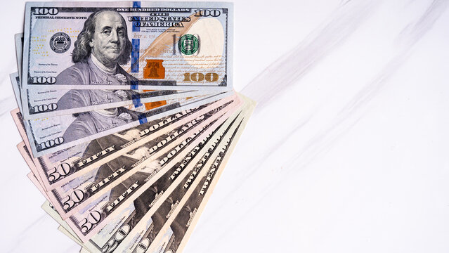 Arrangement of US dollar bills on white marble surface
