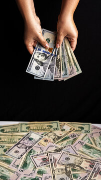 Hands Holding US Dollar Bills Above Money Spread