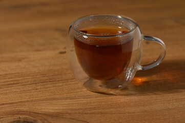 A steaming cup of aromatic tea rests on a rustic wooden table, inviting warmth and comfort during a cozy afternoon