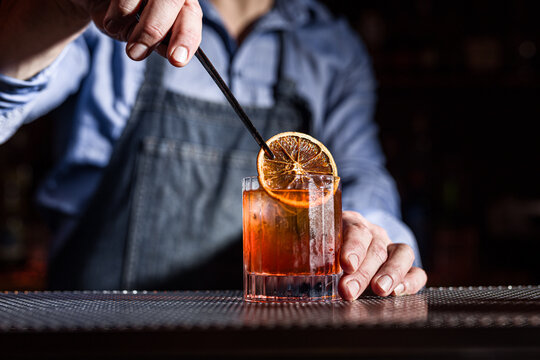 Bartender Crafting a Perfect Whiskey Cocktail with Orange Garnish