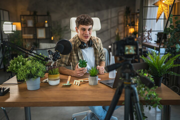 young man blogger blogging about care of house plants at home studio