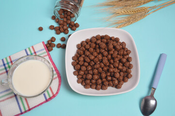 Breakfast of chocolate cereal and fresh milk. Chocolate balls on a bowl with a blue background. top view
