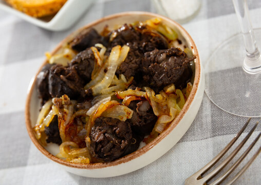 Spanish blood sausage morcilla served with grilled onion on plate