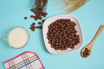 Breakfast of chocolate cereal and fresh milk. Chocolate balls on a bowl with a blue background. top view
