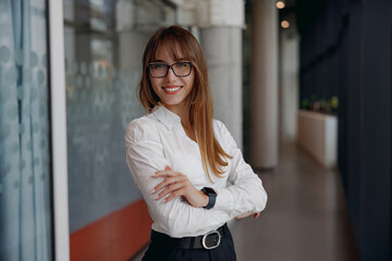 A professional woman stands with confidence and poise in a modern and contemporary office environment