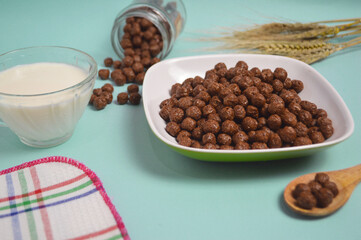 Breakfast of chocolate cereal, cornflakes and fresh milk. A bowl of breakfast cereal is served on a blue background. Top view
