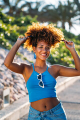 Beautiful smiling black woman playing with her afro hair in the street