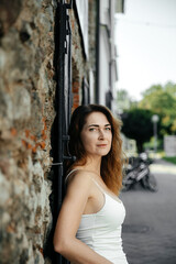Woman in white dress leaning on stone wall outdoors