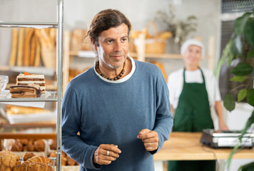 Adult male shopper looking around in bakery choosing pastries