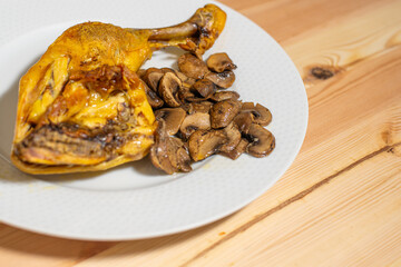 oven roasted chicken thigh with sliced mushrooms on a white plate on a wooden table