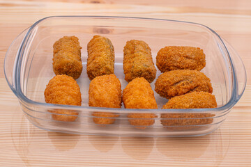 Chicken mushroom and cod croquettes arranged in a glass container on a wooden table