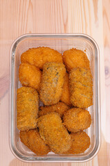 Chicken mushroom and cod croquettes arranged in a glass container on a wooden table