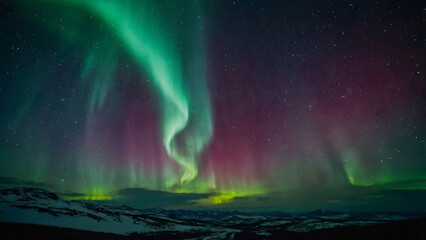 Northern Lights Over Snowy Mountain Landscape. Stunning aurora borealis with green and purple hues dancing over a serene snowy mountain landscape under a starry night sky.
