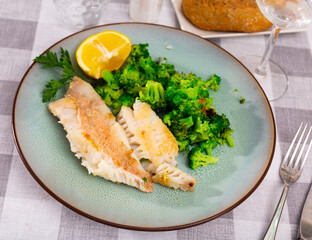 Appetizing fillet of gallineta with broccoli, garnished with a slice of lemon and a sprig of parsley