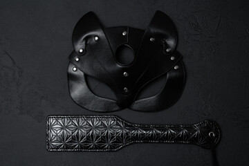 Black leather mask and adult toy on a white background, top view