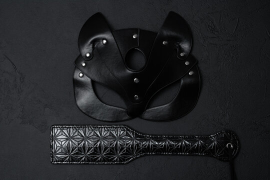 Black leather mask and adult toy on a white background, top view
