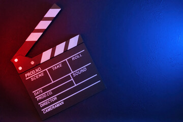Clapperboard on black background with red and blue light, top view