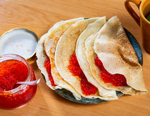 Delicious pancakes served on plate with red caviar..