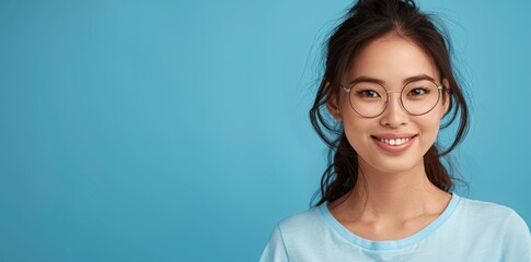 Smiling Asian Woman in Glasses and T-Shirt on Blue Background