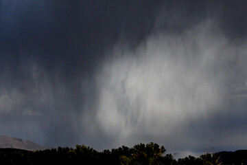 Rain squalls dropping from dark clouds, Highway 395, Topaz, Nevada