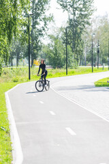 Naklejka premium Caucasian woman riding a bike in a park. Vertical photo. 
