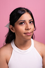 Hispanic woman's face with makeup test on pink background