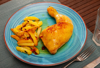 Braised chicken with baked potatoes on a ceramic plate cooked in a cafe