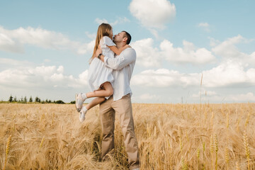 Happy child and dad hugging in a rye field.